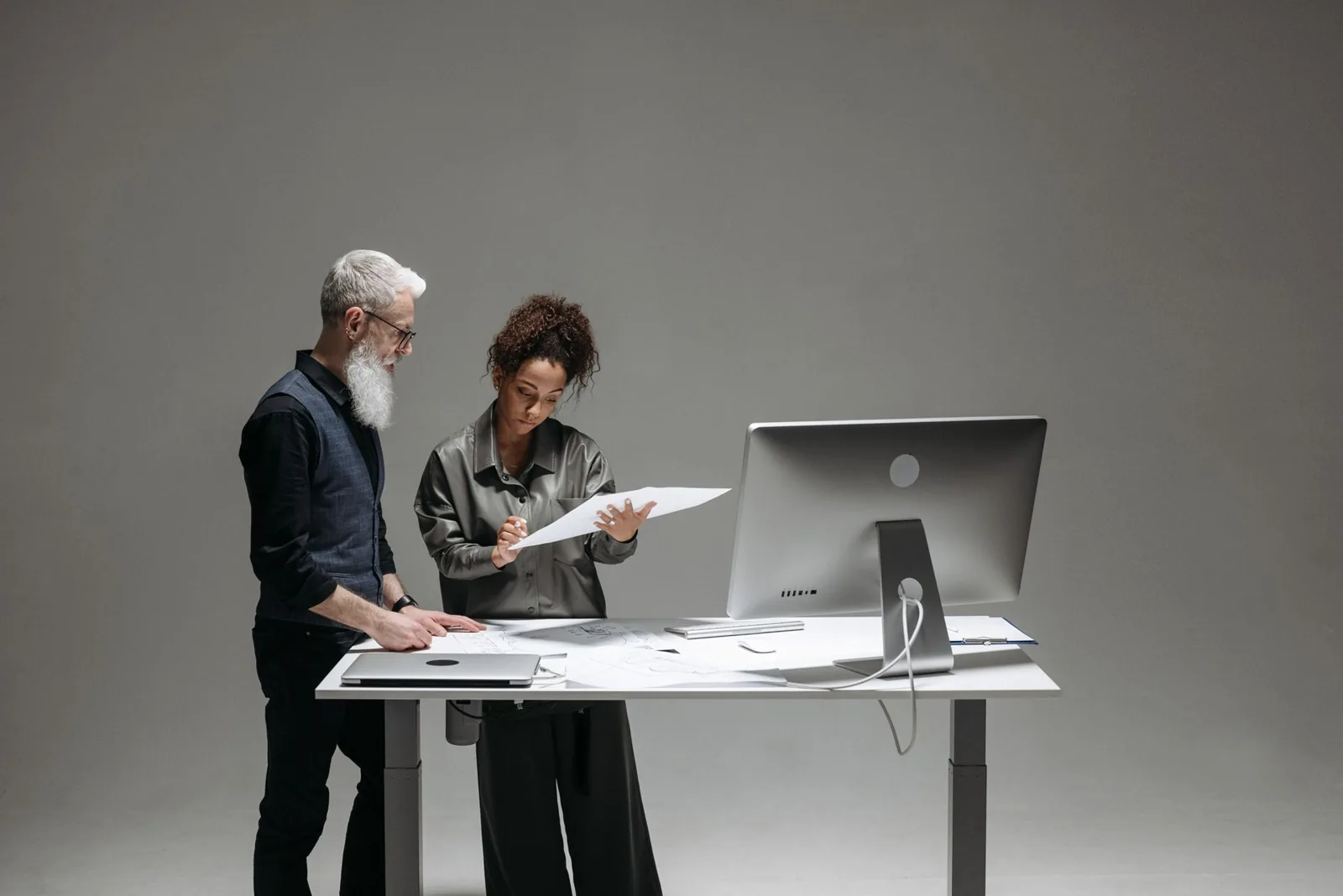Profesionales contrastando documentos junto a un monitor